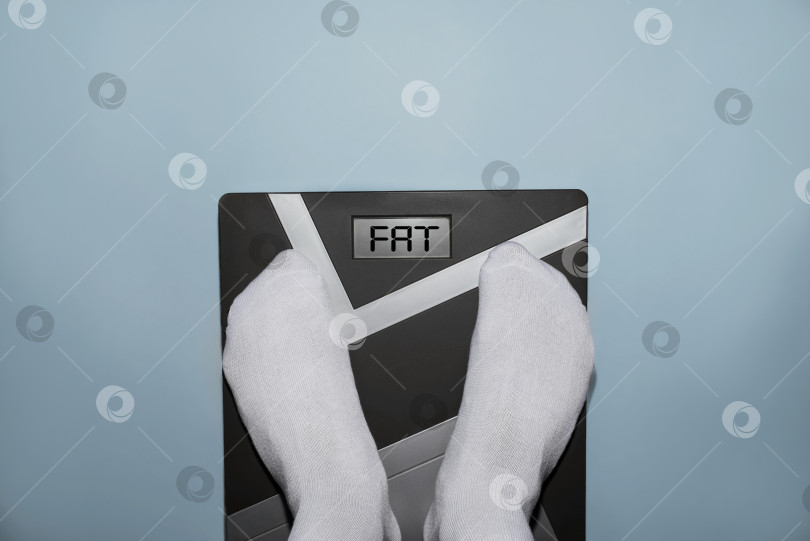 Скачать Человек на электронных весах, дисплей показывает количество жира. Избыточный вес, ожирение, ленивый образ жизни, концепция диеты. Вид сверху, от первого лица фотосток Ozero
