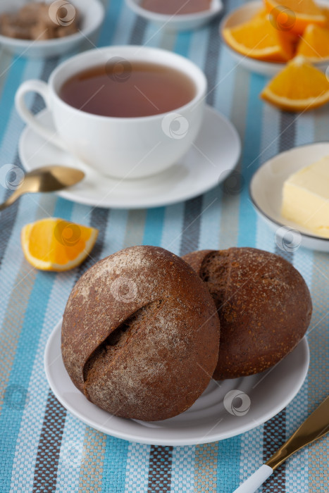 Скачать Ржаные булочки и сливочное масло для завтрака с чаем и апельсином фотосток Ozero