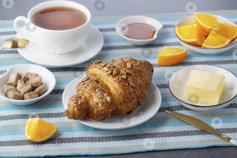 Скачать Свежий круассан с маслом и чаем, апельсин на завтрак фотосток Ozero