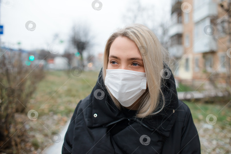 Скачать Молодая женщина в медицинской маске на улице. Портрет девушки, смотрящей в сторону зимой фотосток Ozero