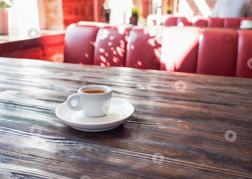 Скачать Кофе в белой чашке стоит на деревянном столе. Прекрасный минималистичный вид за чашечкой кофе в солнечном кафе. фотосток Ozero