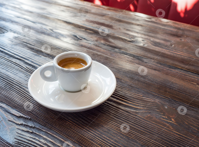 Скачать Кофе в белой чашке стоит на деревянном столе. Прекрасный минималистичный вид за чашечкой кофе в солнечном кафе. фотосток Ozero