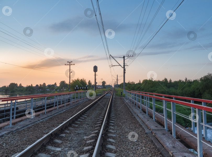 Скачать Железнодорожные пути на мосту в сельской местности вечером фотосток Ozero