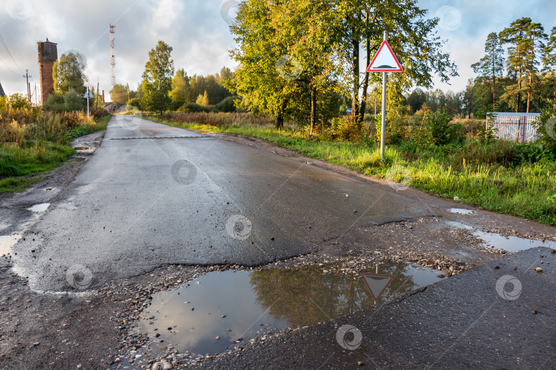 Скачать Сельская дорога. Колея с лужами. Дорожный знак фотосток Ozero