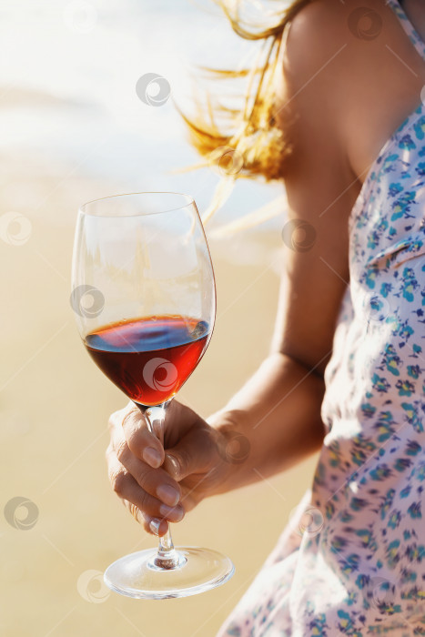 Скачать Бокал красного вина в руках девушки на фоне береговой линии, крупный план фотосток Ozero