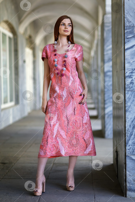 Скачать Молодая красивая девушка позирует в бесшовном платье, выполненном в авторской технике из шерсти мериноса в розово-персиковой гамме, демонстрирует дизайнерскую одежду фотосток Ozero