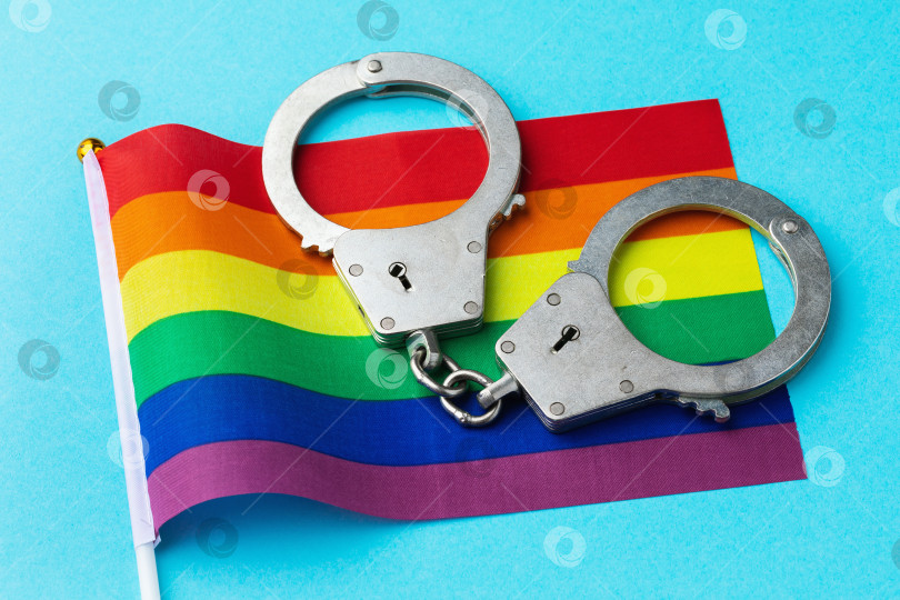Скачать Наручники и радужный флаг на цветном фоне, концепция на тему наказания за пропаганду ЛГБТ-культуры фотосток Ozero