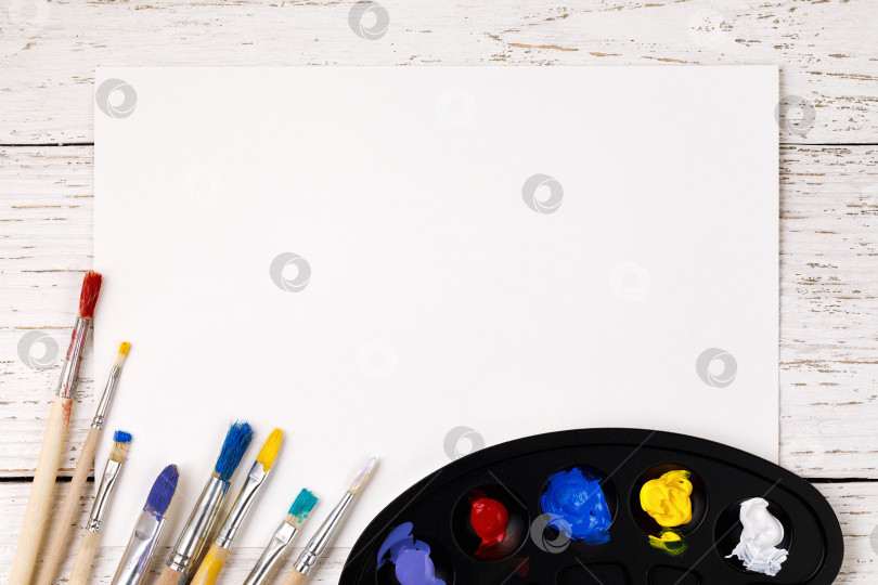 Скачать Художественные принадлежности: палитра с красками и кисточками для рисования на деревянном столе с местом для текста фотосток Ozero
