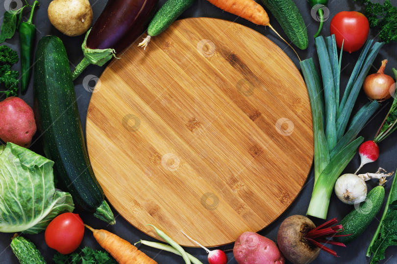 Скачать Вид сверху на пустую разделочную доску, окруженную различными овощами, фон еды фотосток Ozero