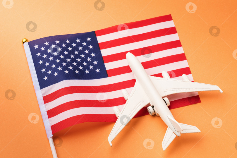 Скачать Флаг Соединенных Штатов Америки и игрушечный самолет на оранжевом фоне, концепция путешествия по Америке фотосток Ozero
