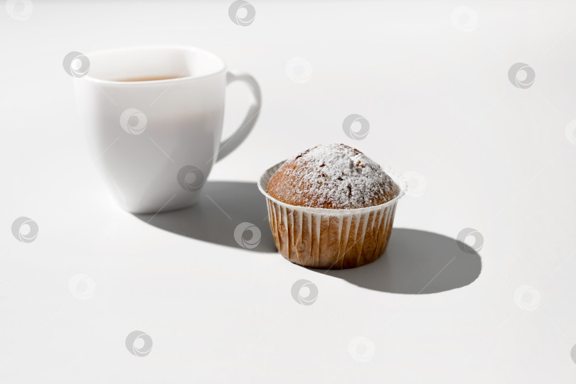 Скачать Утренний завтрак с кексом. Чашка чая и булочка на белом столе. фотосток Ozero