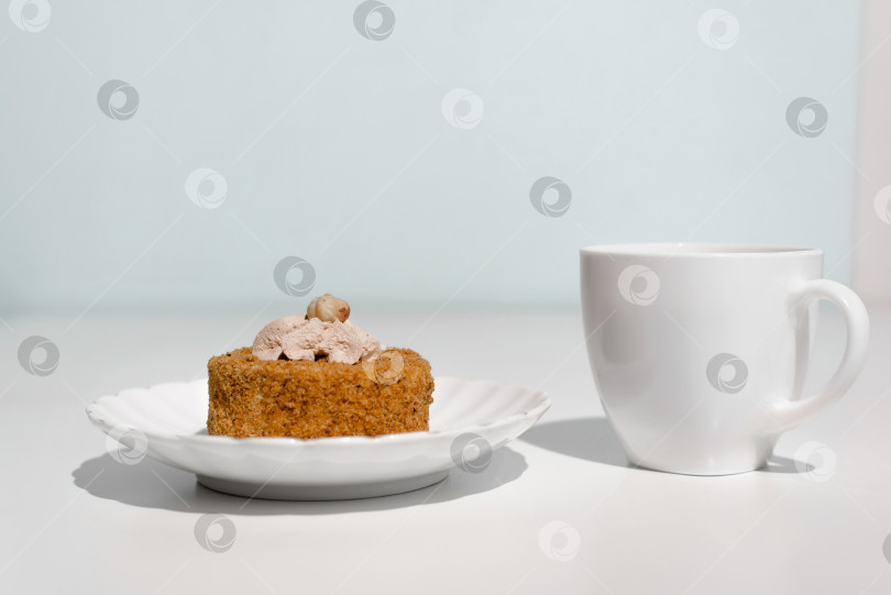 Скачать Чашка чая и торт, украшенный кремом и орехами. Утренний завтрак с десертом на кухне. фотосток Ozero