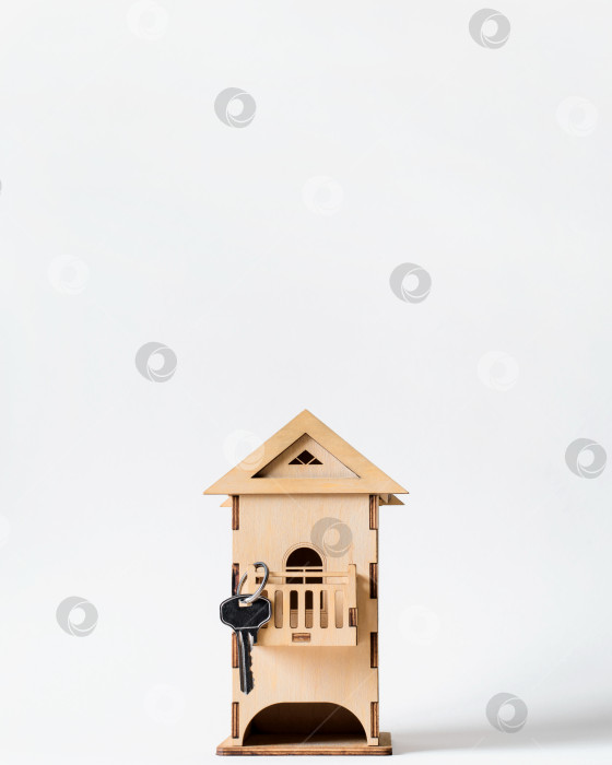 Скачать Деревянный игрушечный домик с ключом на светлом фоне, копирующий пространство. Концепция покупки (аренды) недвижимости, продажи дома фотосток Ozero