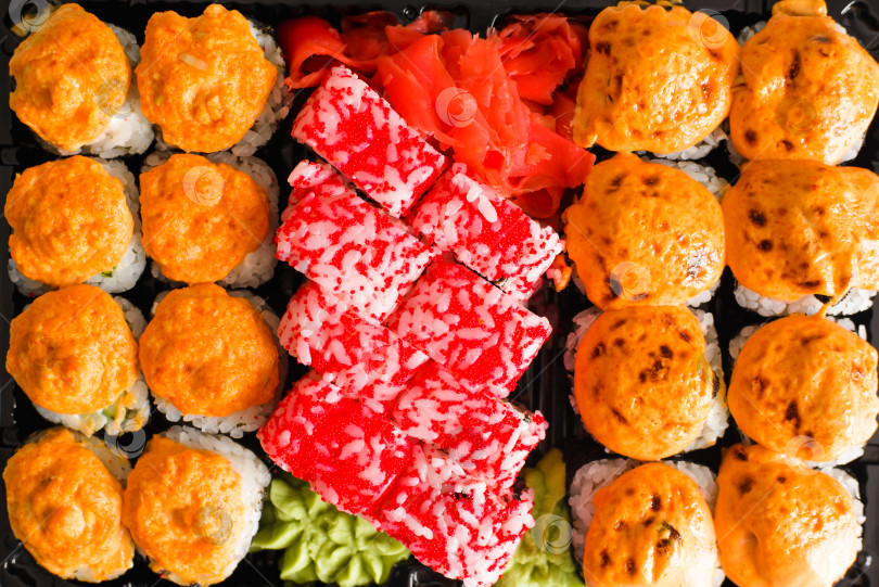 Скачать Традиционная японская еда - суши и роллы крупным планом. Набор запеченных и калифорнийских роллов в пластиковом контейнере, вид сверху фотосток Ozero