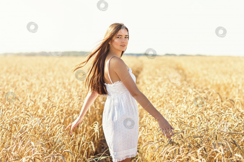 Скачать Девушка в белом платье на фоне поля со спелой пшеницей. Модель позирует теплым летним утром фотосток Ozero