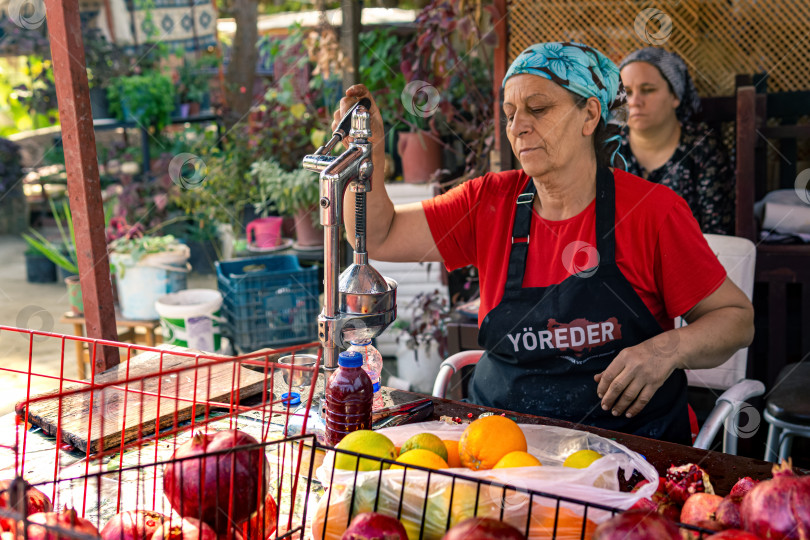 Скачать женщина, продающая свежевыжатый гранатовый сок в Кемере, Турция фотосток Ozero