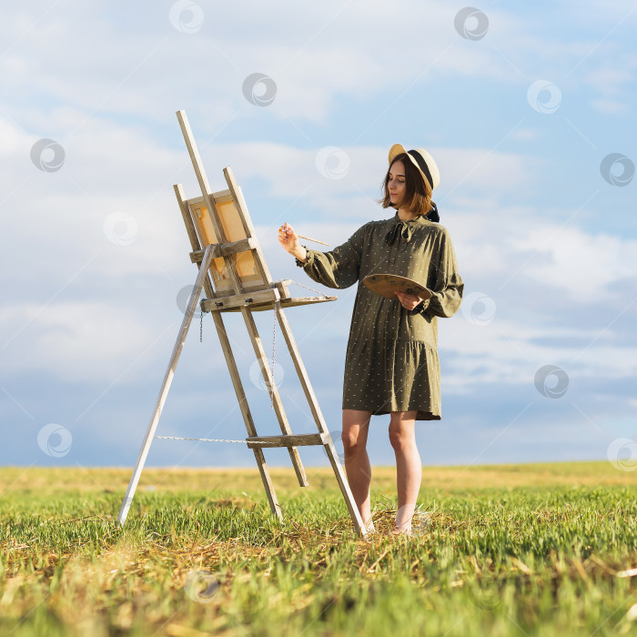 Скачать Молодая красивая женщина-художник пишет картину на природе теплым летним солнечным вечером фотосток Ozero