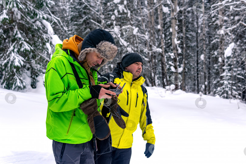 Скачать оператор с помощником управляет дроном из зимнего леса фотосток Ozero