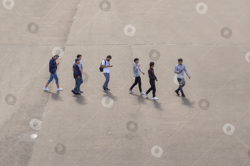 Скачать Москва - 31 июля 2020 года: Группа парней азиатского происхождения переходит улицу. Вид с высоты птичьего полета фотосток Ozero