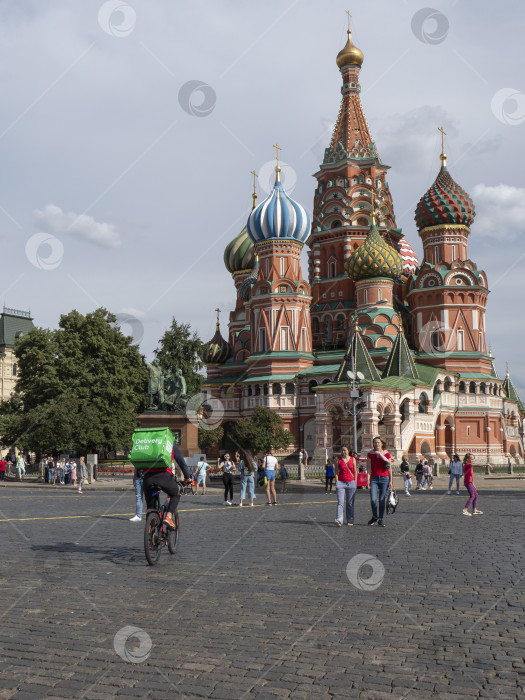 Скачать Москва - 30 июля 2020 года: Доставка еды. Велосипедист развозит еду по Красной площади в Москве фотосток Ozero