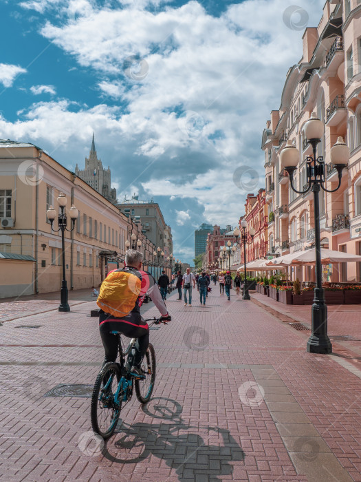 Скачать Велосипедист с рюкзаком за спиной едет по улице Арбат в Москве фотосток Ozero