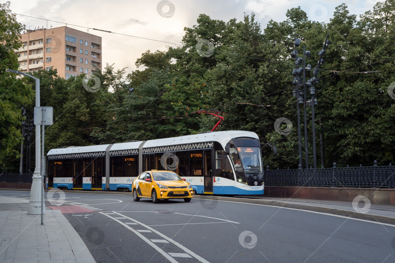 Скачать Москва, 31 июля 2020 года. Россия, городское желтое такси и трамвай на повороте дороги фотосток Ozero