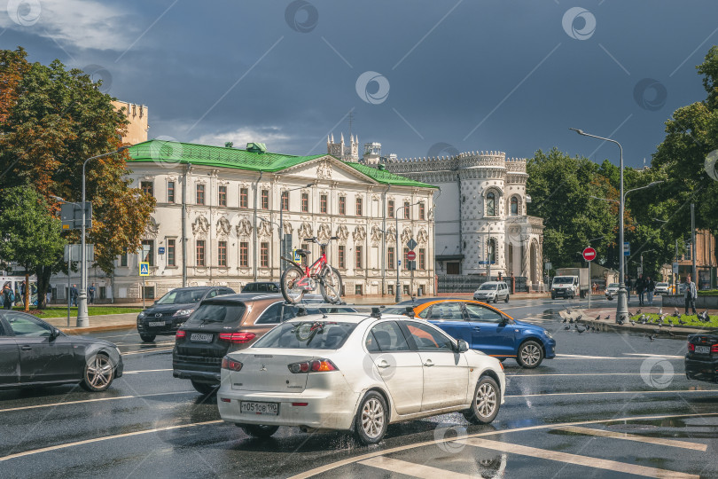 Скачать Россия, Москва, 31 июля 2020 года. Велосипед на крыше белого автомобиля везут по улице. Уличная динамика с движением автомобилей и людей, идущих по улице фотосток Ozero