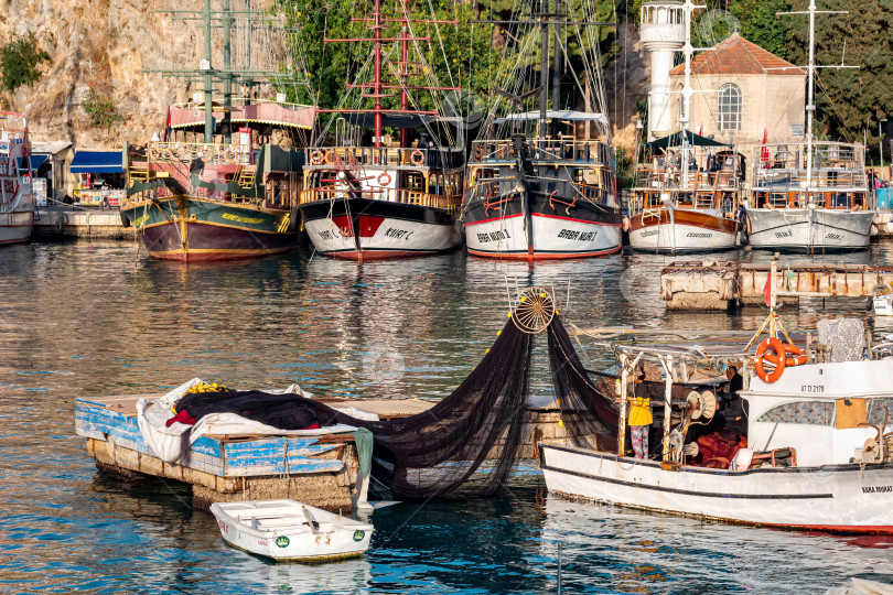 Скачать рыбаки проверяют сети на рыбацкой лодке на фоне прогулочных судов в винтажном стиле в древней гавани Анталии фотосток Ozero