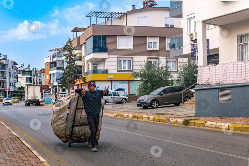 Скачать сборщик пластиковых отходов и вторсырья с огромным мешком в жилом районе Анталии фотосток Ozero