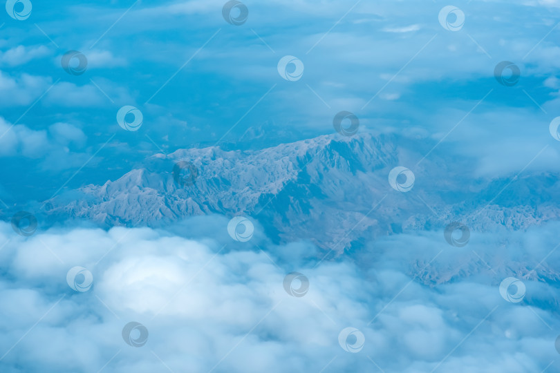 Скачать вид на землю внизу во время полета над облаками, горная местность сквозь атмосферную дымку, вид сверху фотосток Ozero