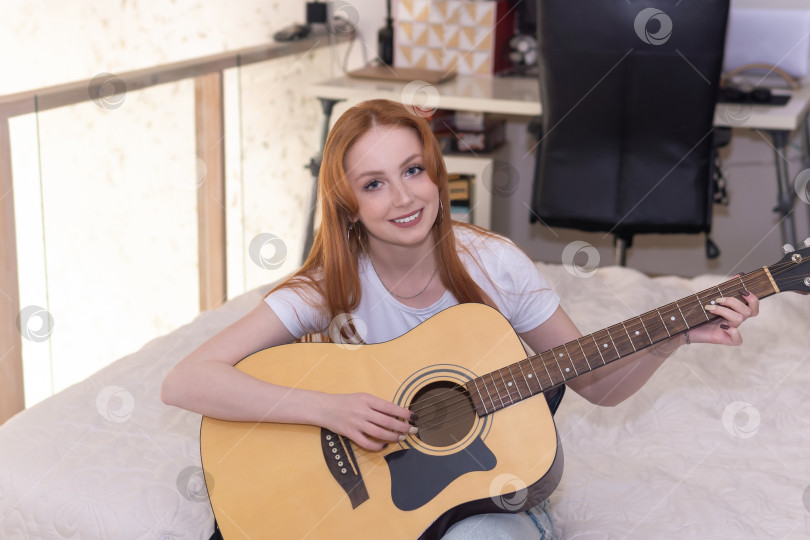 Скачать молодая женщина играет на акустической гитаре дома фотосток Ozero