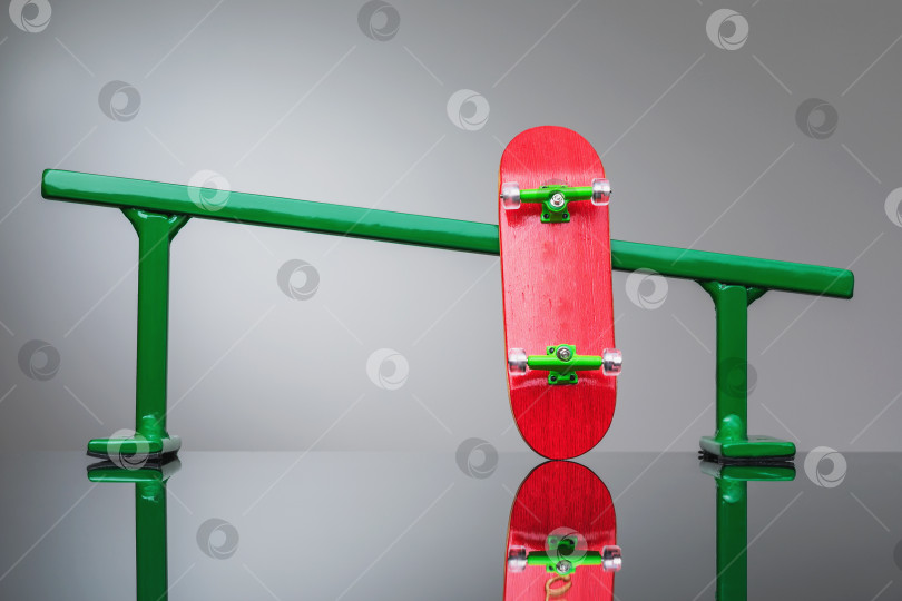 Скачать Металлические перила зеленого цвета и маленький деревянный скейтборд на градиентном фоне фотосток Ozero