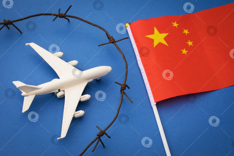 Скачать Игрушечный самолет, флаг и ржавая колючая проволока на цветном фоне, концепция закрытой воздушной границы Китая фотосток Ozero