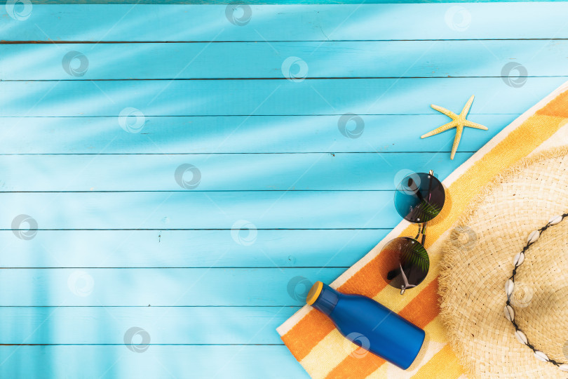 Скачать Полотенце, шляпа, солнцезащитные очки, солнцезащитный крем и морская звезда на синем деревянном фоне с пробелом для копирования фотосток Ozero