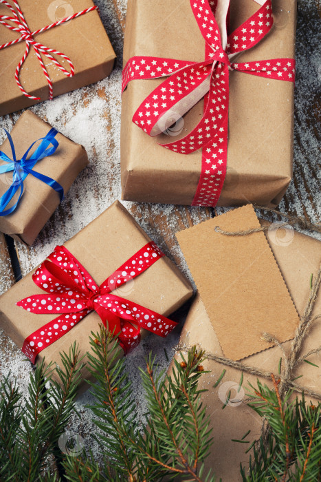 Скачать Разные новогодние подарки, завернутые в оберточную бумагу, лежат под веткой рождественской елки. Вид сверху фотосток Ozero