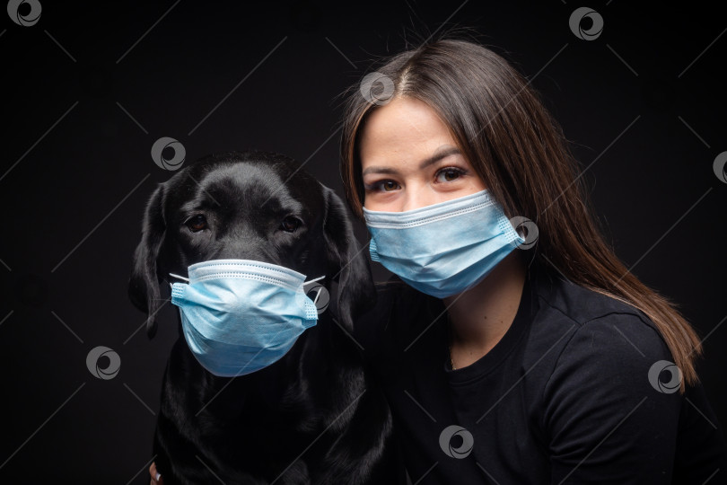 Скачать Портрет собаки породы лабрадор-ретривер в защитной медицинской маске с хозяйкой женского пола. фотосток Ozero