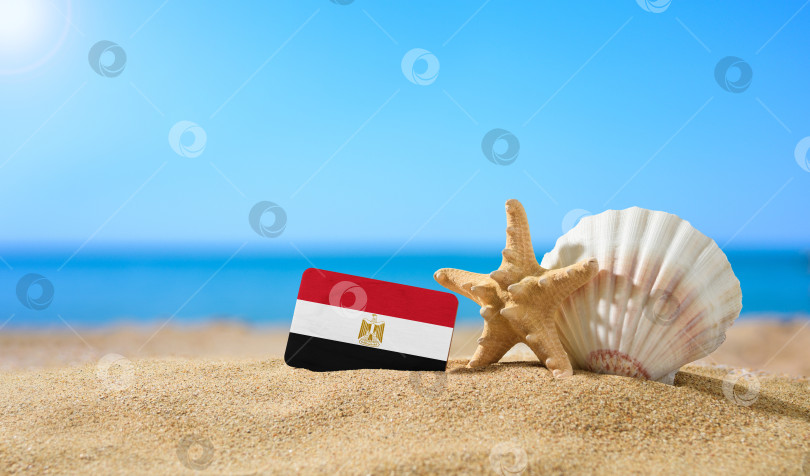 Скачать Тропический пляж с ракушками и египетским флагом. Концепция райского отдыха на пляжах Египта. фотосток Ozero