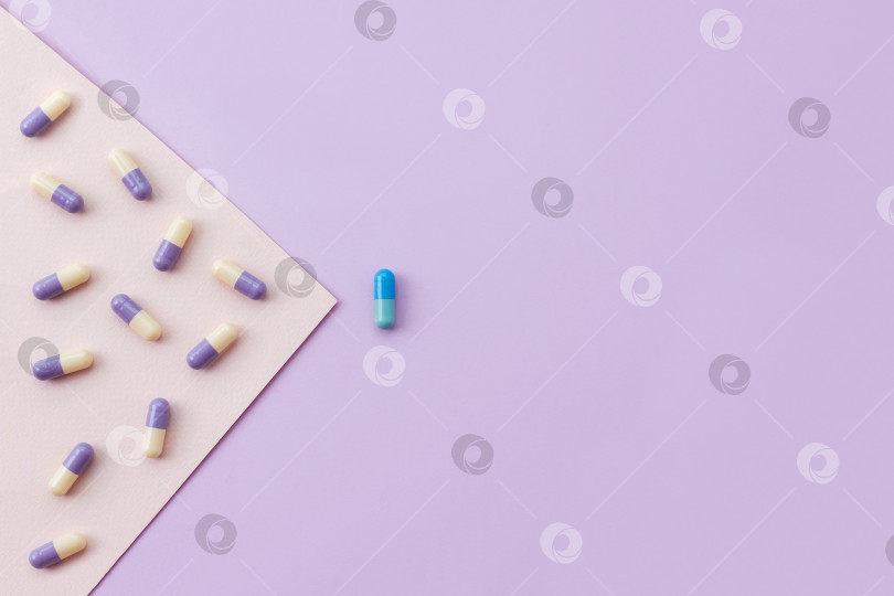 Скачать Множество лекарственных капсул против одной таблетки на разноцветном пастельном фоне. Концепция эффекта плацебо. Место для вашего текста. фотосток Ozero