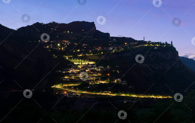 Скачать ночной вид на горную деревню со светящимися фонарями на утесе фотосток Ozero