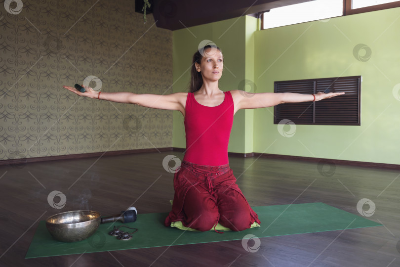 Скачать Женщина, практикующая йогу, занимающаяся медитацией с палочками в руках и различными благовониями, сидящая на коврике в комнате фотосток Ozero