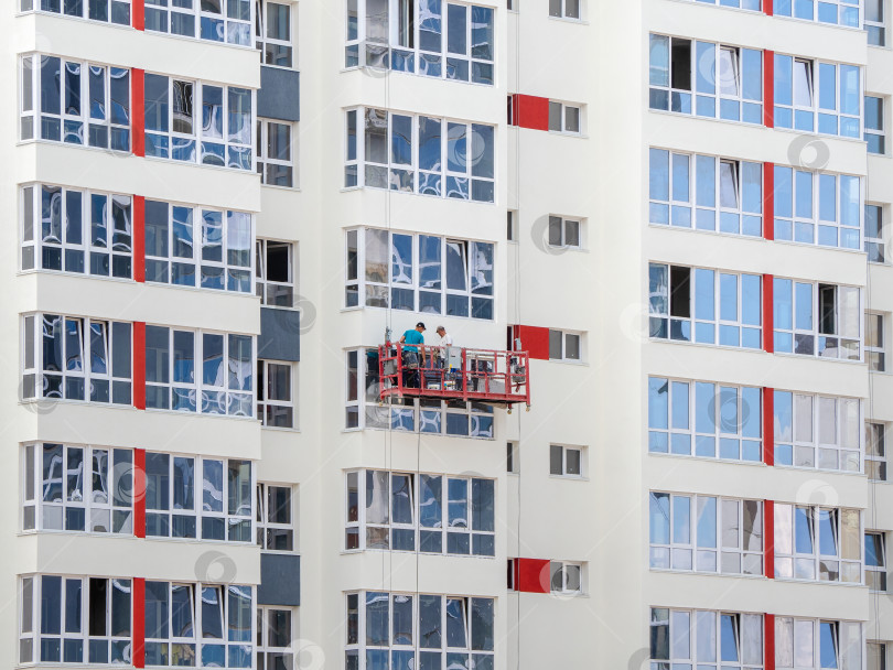 Скачать Лебедка с рабочими на фасаде нового строящегося здания. фотосток Ozero
