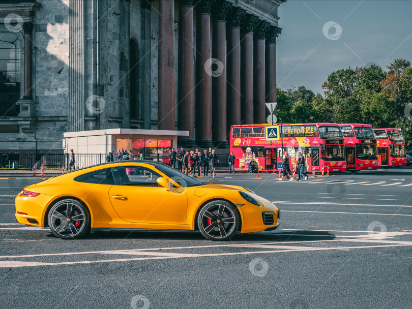 Скачать Желтый Porsche 911 припаркован на открытом воздухе у Исаакиевского собора в Санкт-Петербурге. фотосток Ozero