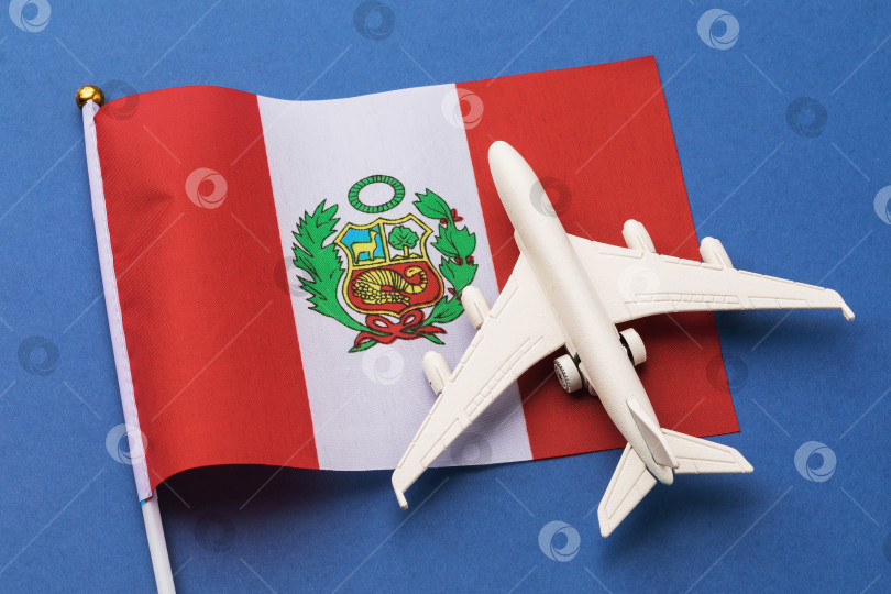Скачать Перуанский флаг и игрушечный самолет на цветном фоне, концепция на тему путешествия в Перу фотосток Ozero