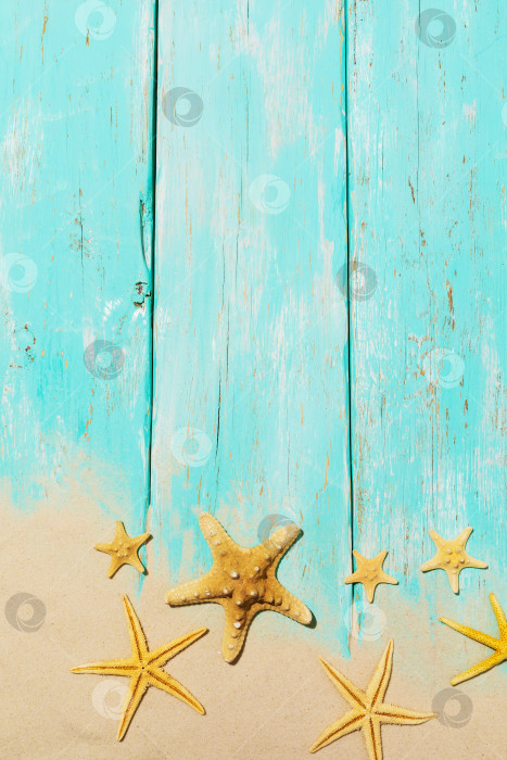 Скачать Различные морские звезды и морской песок на синем деревянном фоне с пробелом для копирования вверху фотосток Ozero