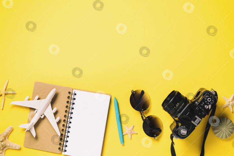 Скачать Игрушечный самолетик на блокноте с очками и фотоаппаратом на желтом фоне с пробелом для копирования. Концепция планирования путешествия фотосток Ozero