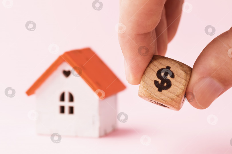 Скачать Мужчина, держащий деревянный куб с символом доллара на фоне дома, концепция стоимости недвижимости фотосток Ozero
