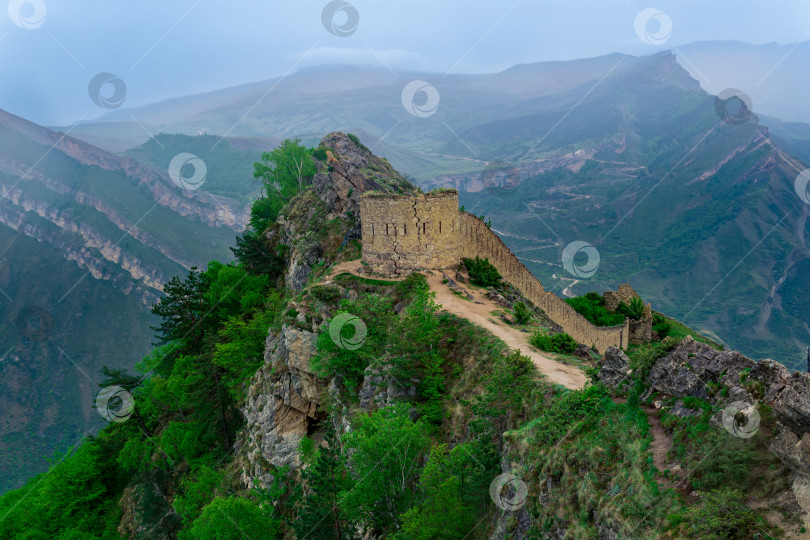 Скачать древняя башня и крепостная стена на вершине отвесной скалы в горной местности, крепость Гуниб (Шамиль) в Дагестане, фотосток Ozero