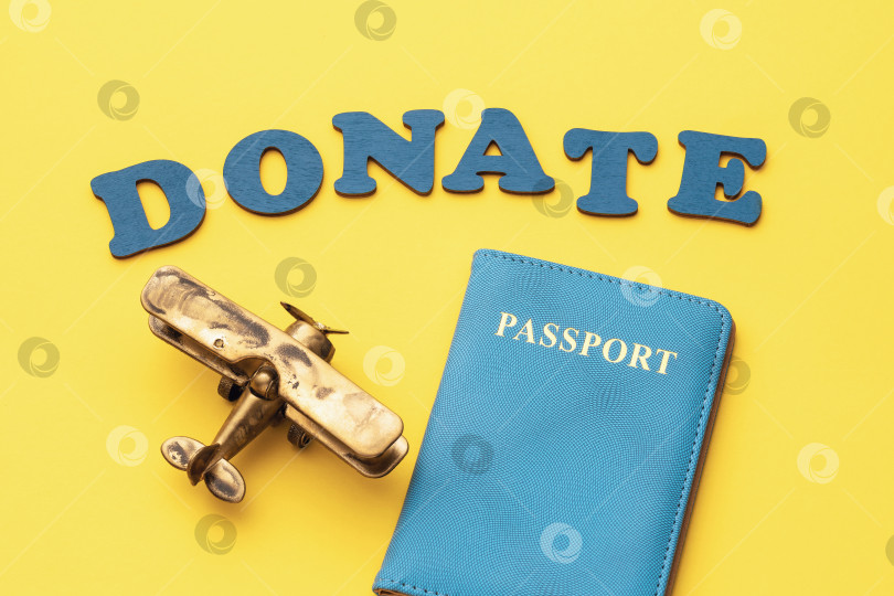 Скачать Слово из деревянных букв, игрушечный самолет и паспорт на желтом фоне, концепция на тему пожертвования за билет фотосток Ozero