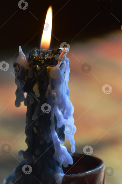 Скачать Светящаяся голубая свеча горит в керамическом подсвечнике в форме туфельки. Вертикальное фото. фотосток Ozero