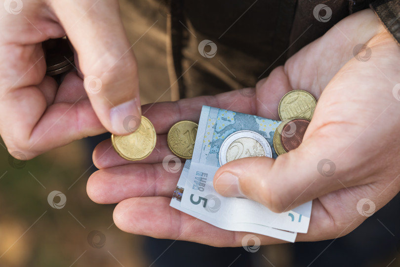 Скачать Мужчина пересчитывает евроценты и мелкие банкноты на ладони фотосток Ozero